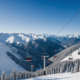 A snowy mountain landscape with ski lifts and a clear sky, indicating a return to normal winter conditions.
